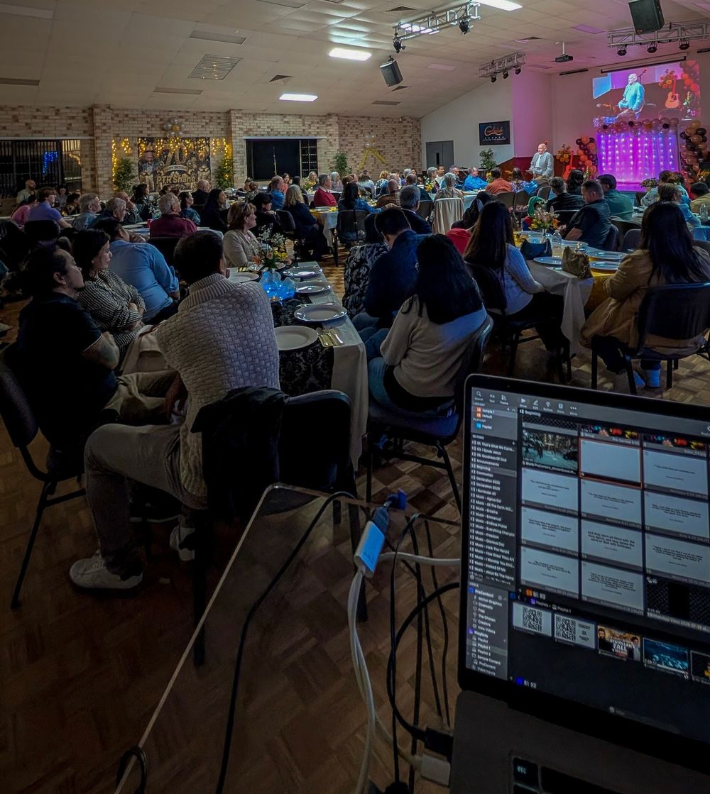 The hall full at a CoastWIDE Church gathering, seen from the back with people seated at long tables