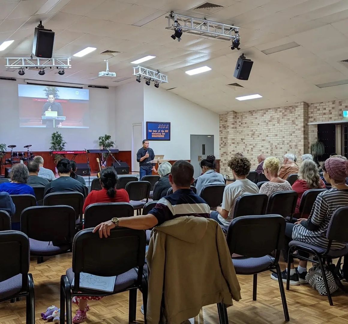 A Sunday evening meeting at CoastWIDE Church in Arundel, Gold Coast, the room full and a speaker at the front