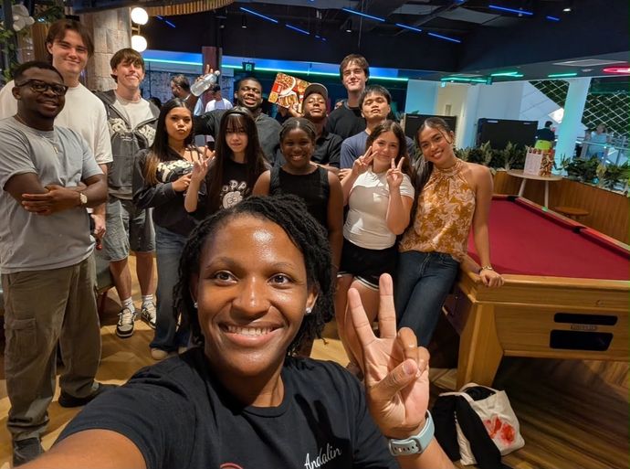 A smiling leader makes a peace sign in a selfie with the CoastWIDE Young Adults, a big group of teens and twenty-somethings behind